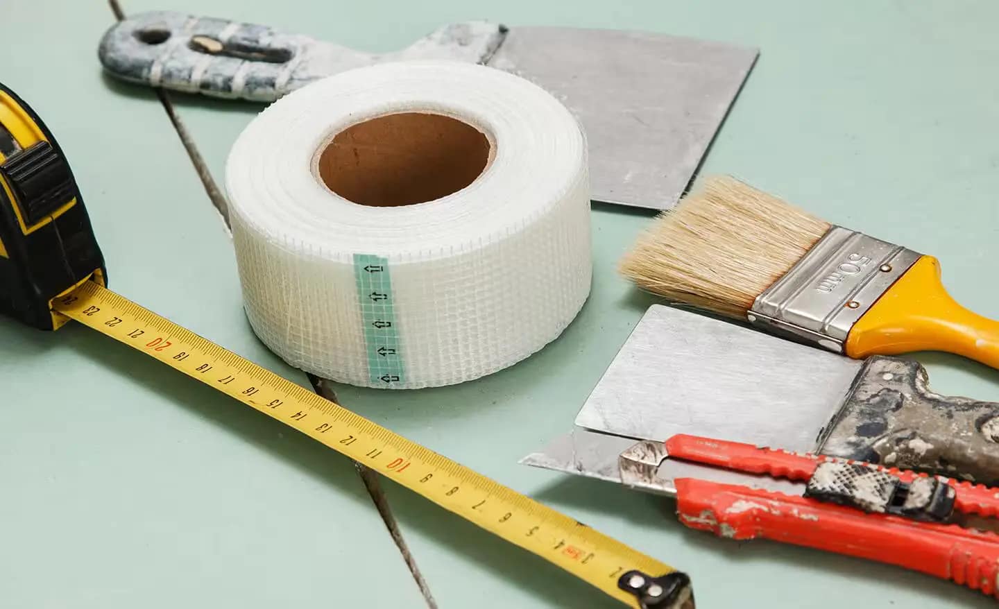 Joint tape being applied over a drywall seam during taping and mudding